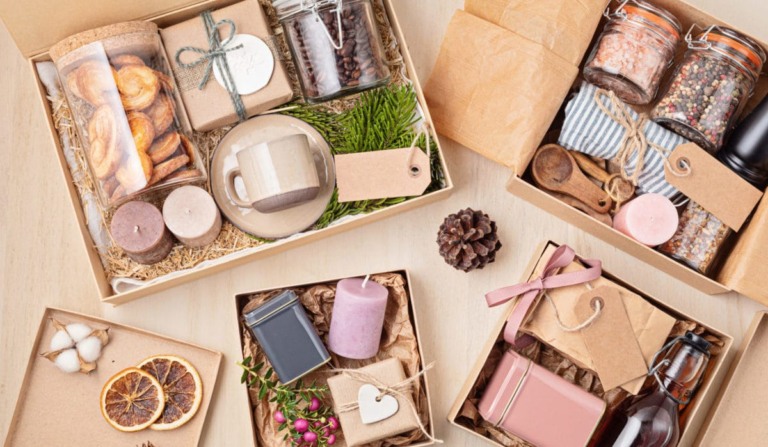 Preparing care package, seasonal gift box with coffee, cookies, candles, spices and cups. Personalized eco friendly basket for family and friends for thankgiving, christmas, mothers and fathers day holidays.